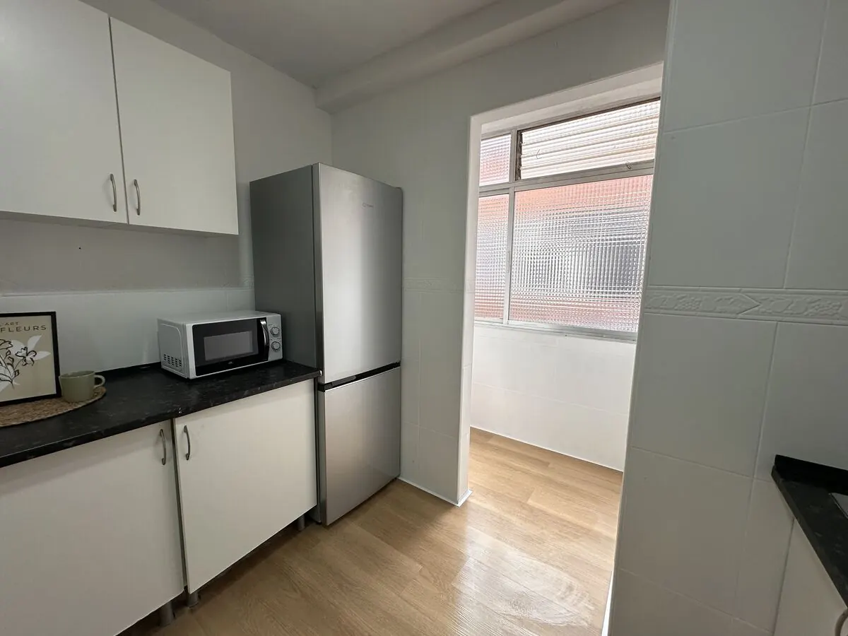 Cocina reformada con muebles blancos y encimera negra