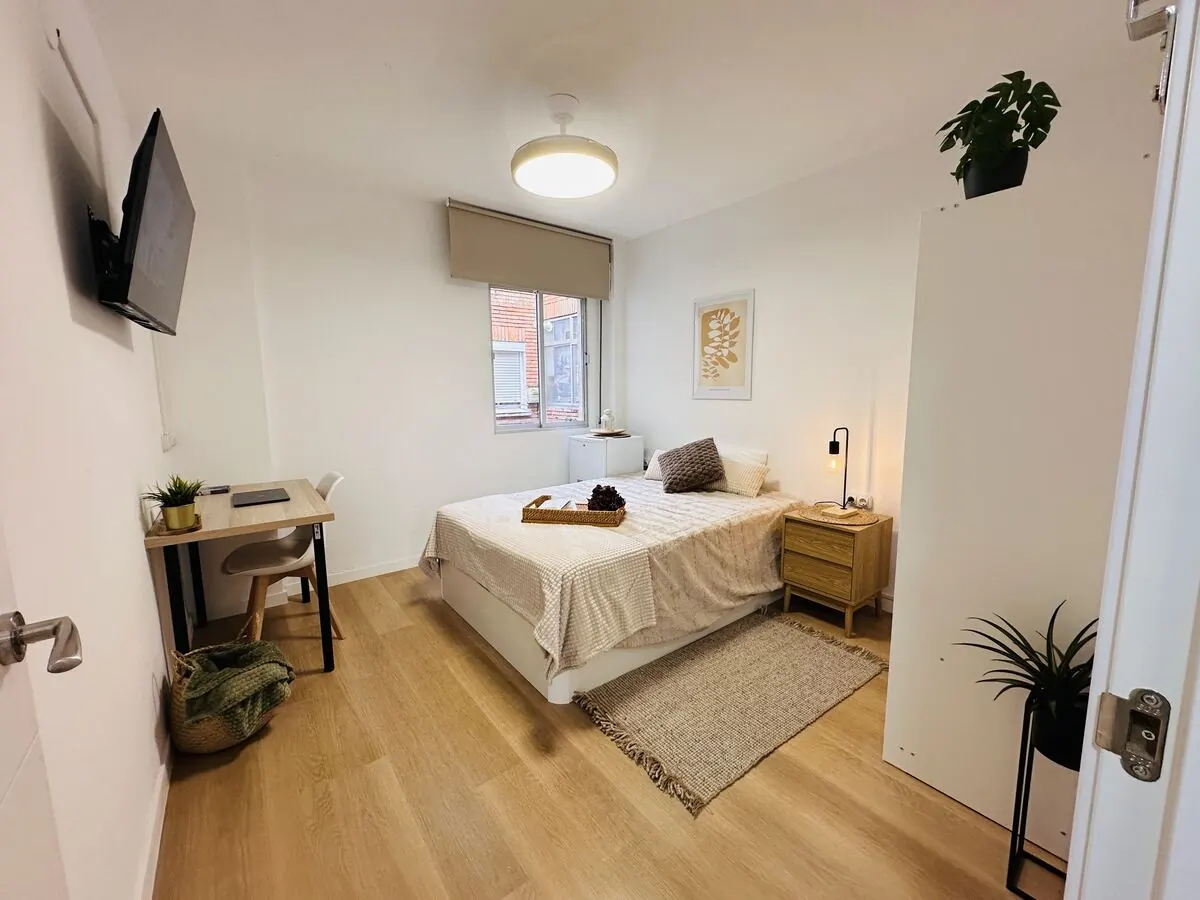 Habitación reformada con escritorio, TV y plantas